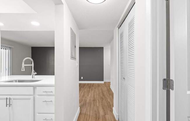 A modern kitchen with white cabinets and a wooden floor.