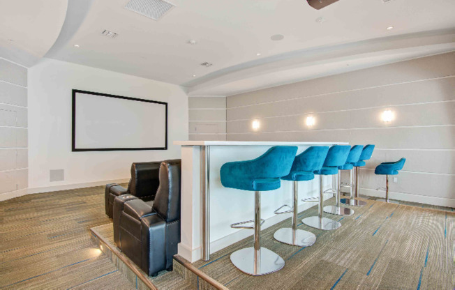 Screening room and theater at our apartments in Miami, featuring chairs, counter seating, and a large screen