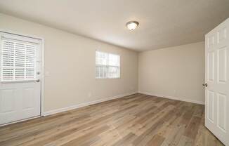 A room with wooden flooring and a window with blinds.