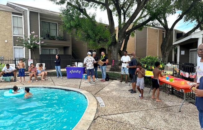 A group of people are gathered around a pool in a backyard.