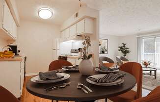 a dining area with a table and chairs and a kitchen in the background