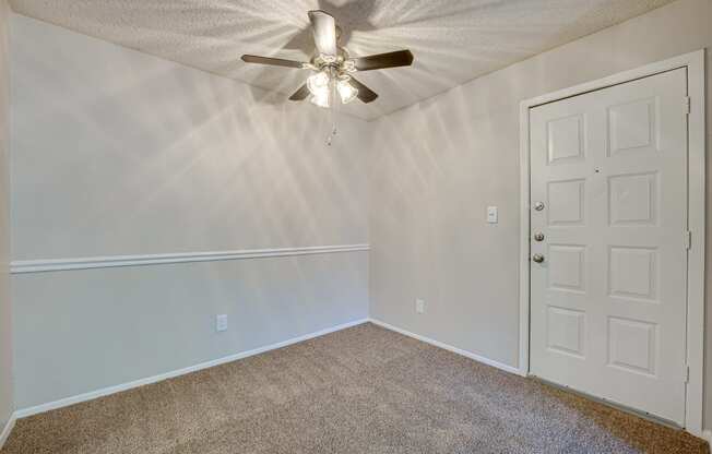 an empty bedroom with a ceiling fan and white door