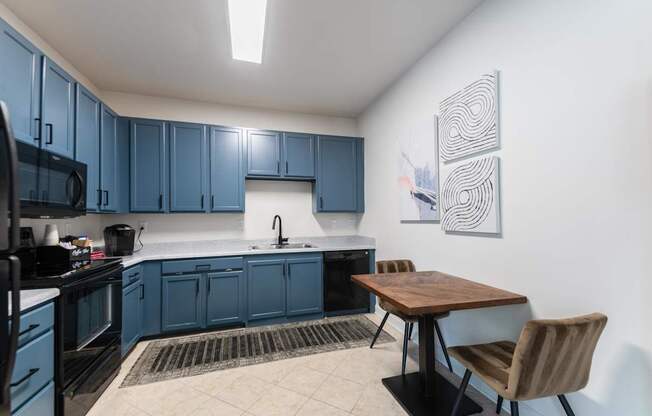 A kitchen with blue cabinets and a wooden table.