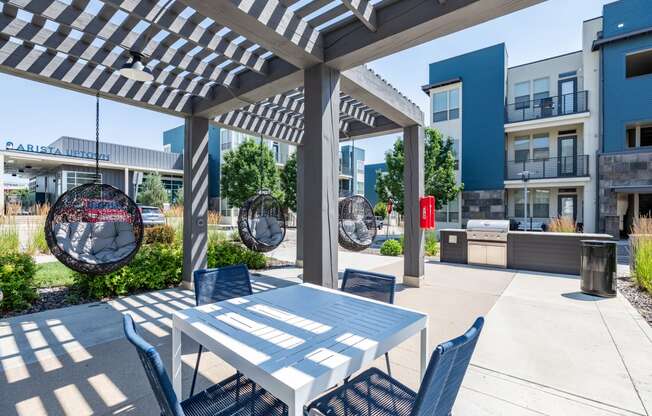 a patio with a white table and blue chairs