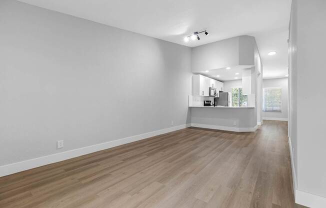 A spacious room with wooden flooring and white walls.