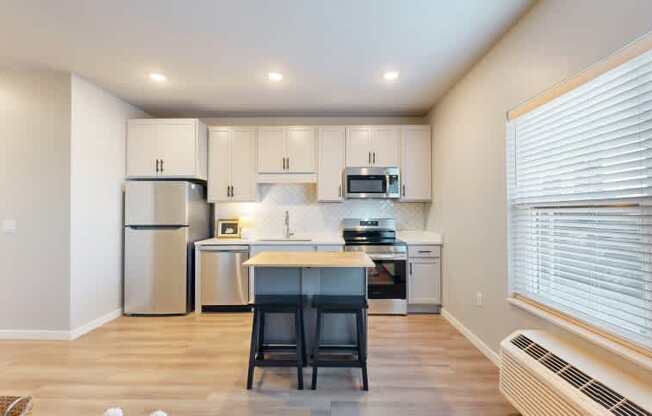A kitchen with a refrigerator, microwave, oven, and sink.