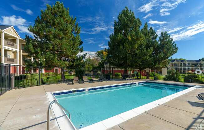 a swimming pool with trees and a building in the background