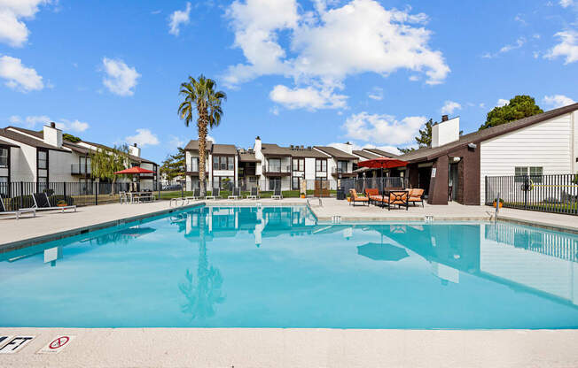 A large swimming pool in front of a building with a palm tree in the background.