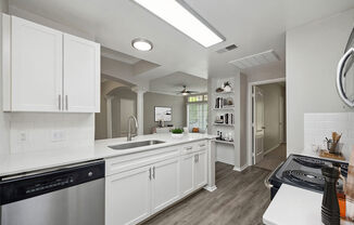 Model Kitchen with Wood-Style Flooring, White Cabinets and View of Living Room Area at Allure North Dallas Apartments located in Dallas, TX.