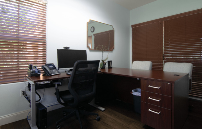 A black office chair is in front of a desk with a computer monitor, keyboard, and mouse.,A black office chair is in front of a desk with a computer monitor, keyboard, and mouse.