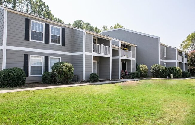 a gray apartment building with a grassy yard