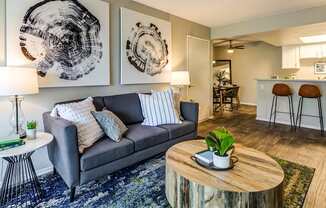 A living room with a grey couch, a wooden coffee table, and two abstract art pieces on the wall.