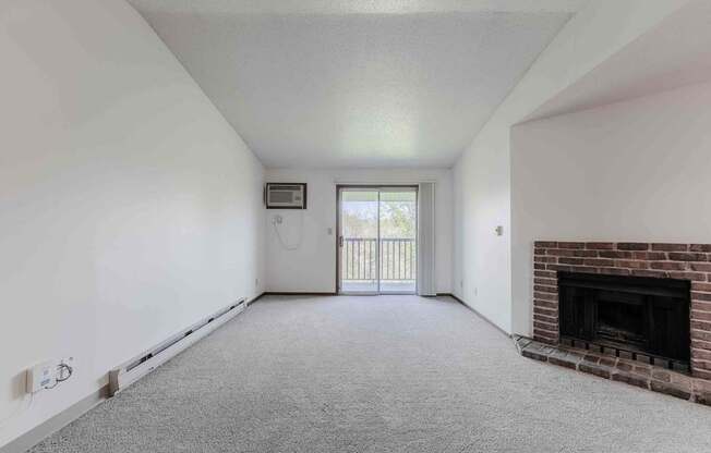 A room with a fireplace and a window with a view of a balcony.