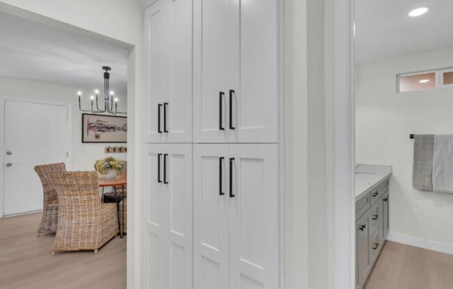 a large white kitchen with white shaker cabinets and a dining room with a table