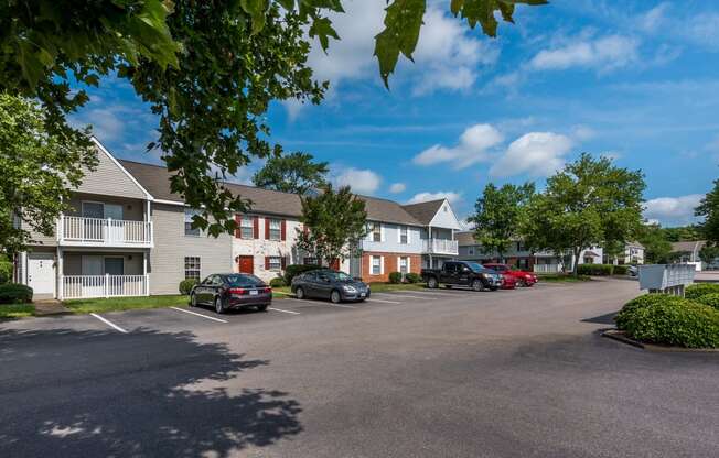 a parking lot with cars parked in front of apartment buildings