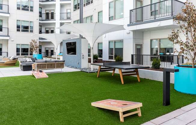 A patio area with a white umbrella, a blue cylindrical object, and a wooden table.