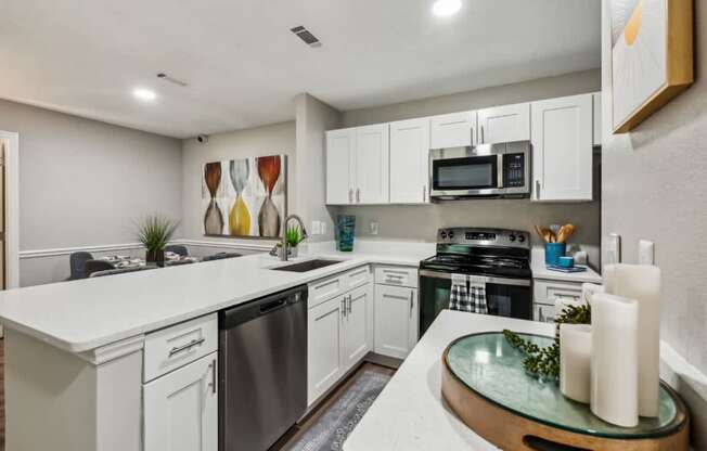 A modern kitchen with white cabinets and stainless steel appliances.