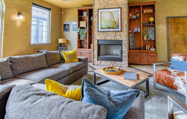 A living room with a grey couch and a fireplace.