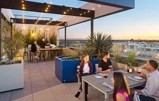 A group of people are sitting around a table on a rooftop patio.