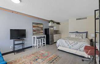 A bedroom with a bed, a chair, and a television.