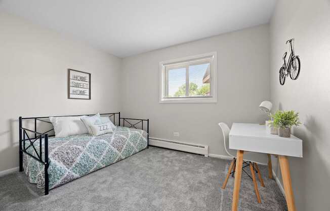 A bedroom with a bed, desk, and a window.