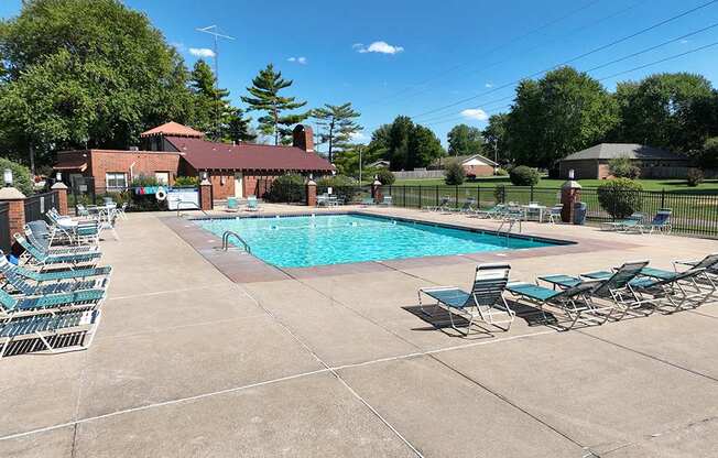 A pool surrounded by chairs and a building in the background at Old Monterey Apartments, Springfield, MO