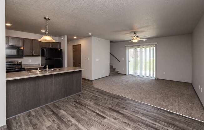 A spacious kitchen with dark wood cabinets and a black refrigerator.
