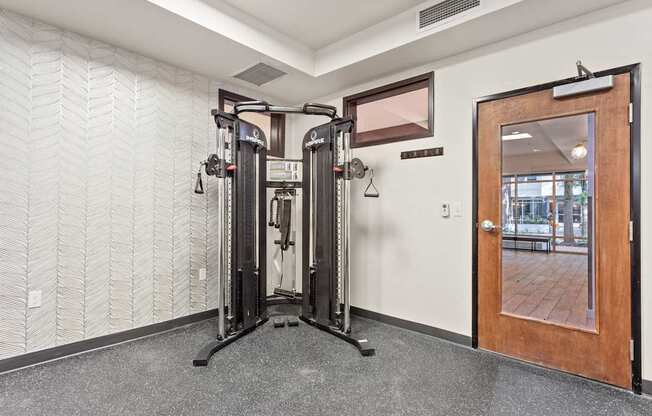 A gym room with a squat rack and a mirror.