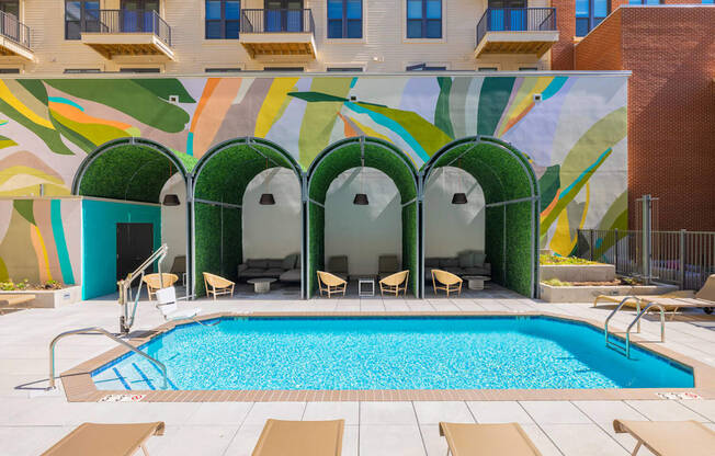 A pool surrounded by chairs and a building with a mural on the side.at The Vale at the Parks, District of Columbia