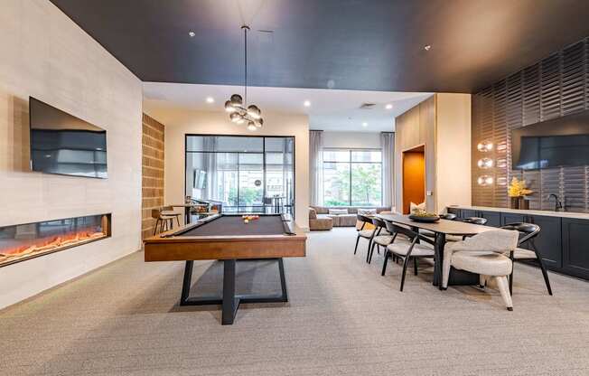 A room with a pool table, a fireplace, and a dining table.