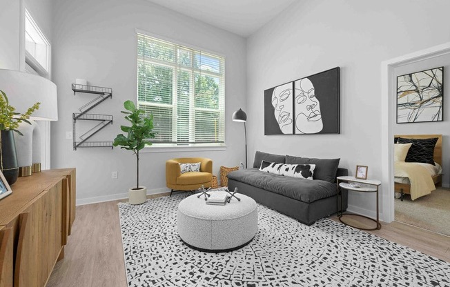 A living room with a grey sofa, yellow armchair, and a black and white patterned rug.