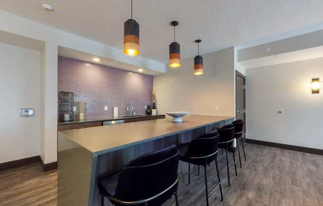 a kitchen with a long counter and a row of black chairs