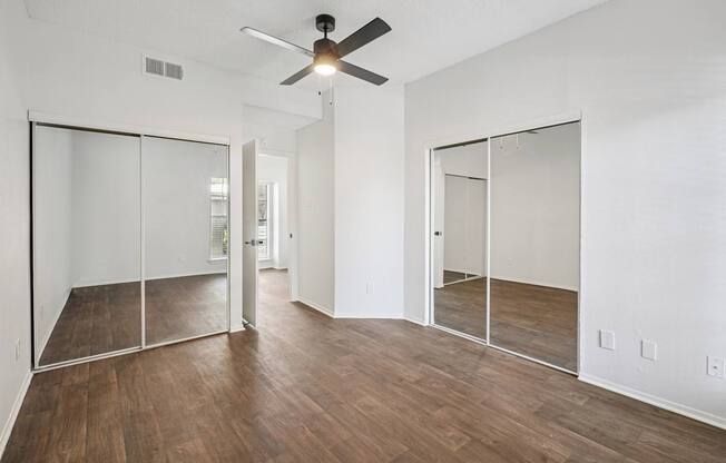 A room with a ceiling fan and sliding glass doors.