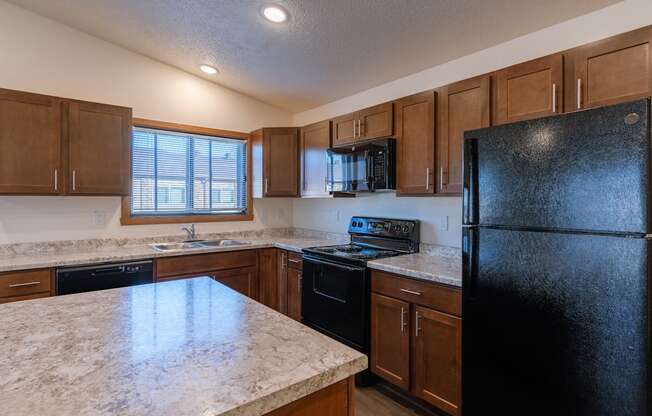 a kitchen with black appliances and white countertops. Fargo, ND Westwood Apartments