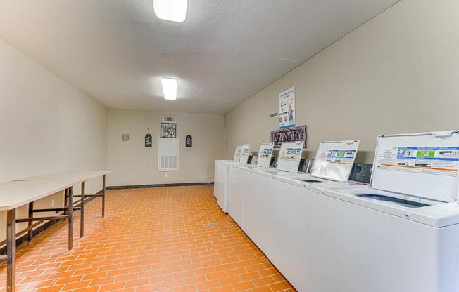 A laundromat with a row of washers and dryers at Copper Hill Apartments, Texas