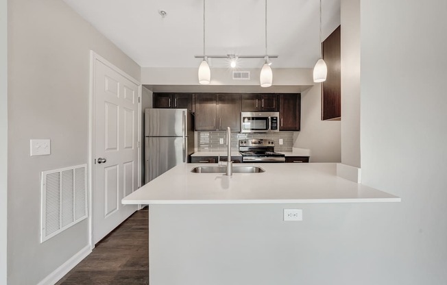 A modern kitchen with a white island and stainless steel appliances.