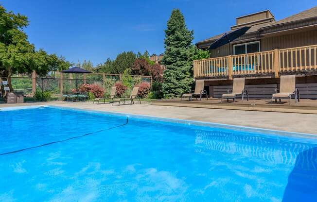 a pool with a deck and a house in the background at Lincoln Village Apartments, Spokane