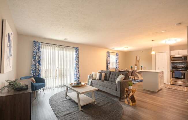 a living room with a couch coffee table and a kitchen in the background