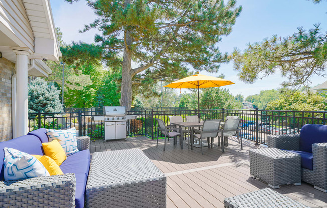 Sun deck with outdoor furniture and table and chairs shaded by a yellow umbrella