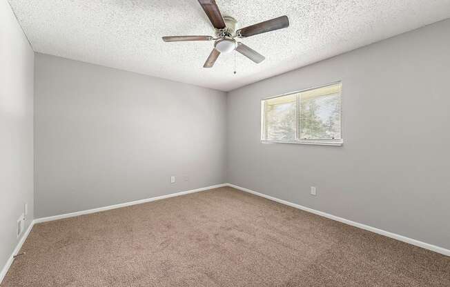 an empty room with a ceiling fan and a window