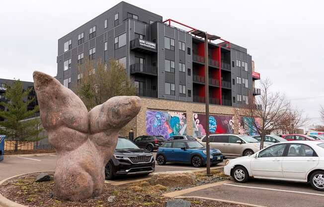 a statue of a hand in front of a parking lot with cars