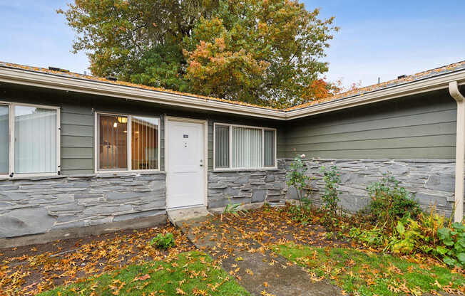 A house with a grey stone wall and a white door.