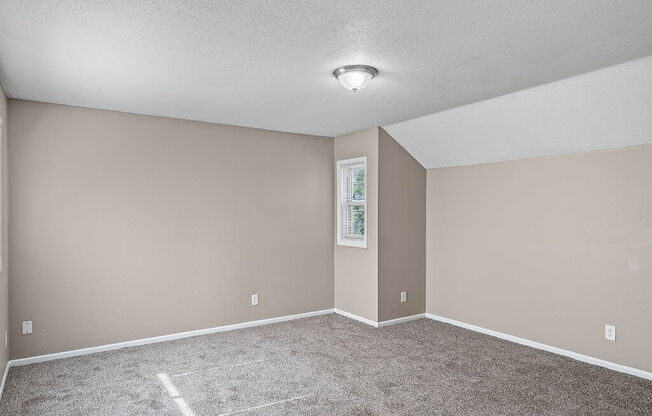an empty living room with carpet and a light on the ceiling