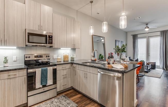 Grapevine TX Apartments - Modern Kitchen With Gray Cabinets, Black Granite Countertops, and Stainless Steel Appliances