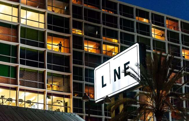 a man stands on a ledge in front of a building with a sign that says ln