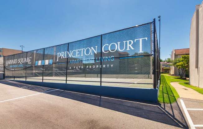 Mesh banner on fencing with Princeton Court and Harvard Square logos next to recreation area at Princeton Court Apartments in the Vickery Midtown neighborhood of Dallas, TX.