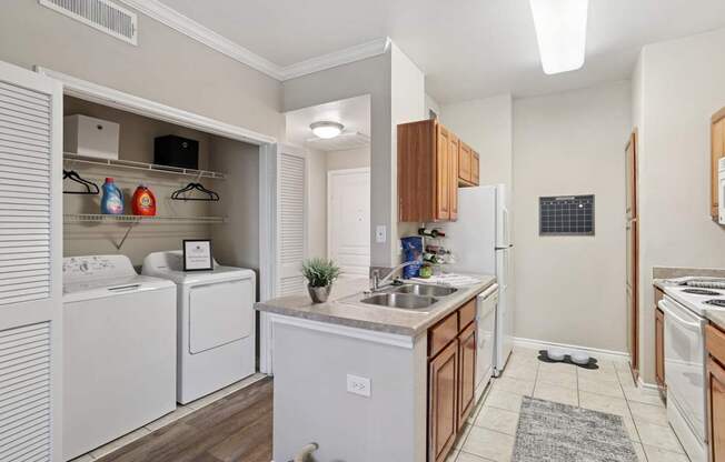 Windsor kitchen with a washer and dryer closet and white kitchen appliances at Encore at Buckingham Apartments in Richardson, TX