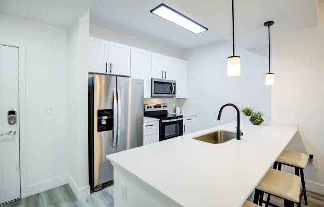 a kitchen with a white counter top and a stainless steel refrigerator