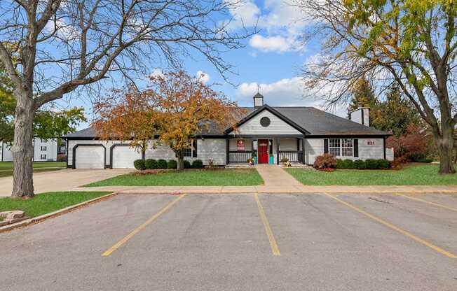 A building with a red door is surrounded by a parking lot.