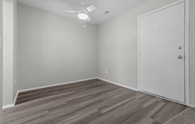 an empty room with wood flooring and a ceiling fan